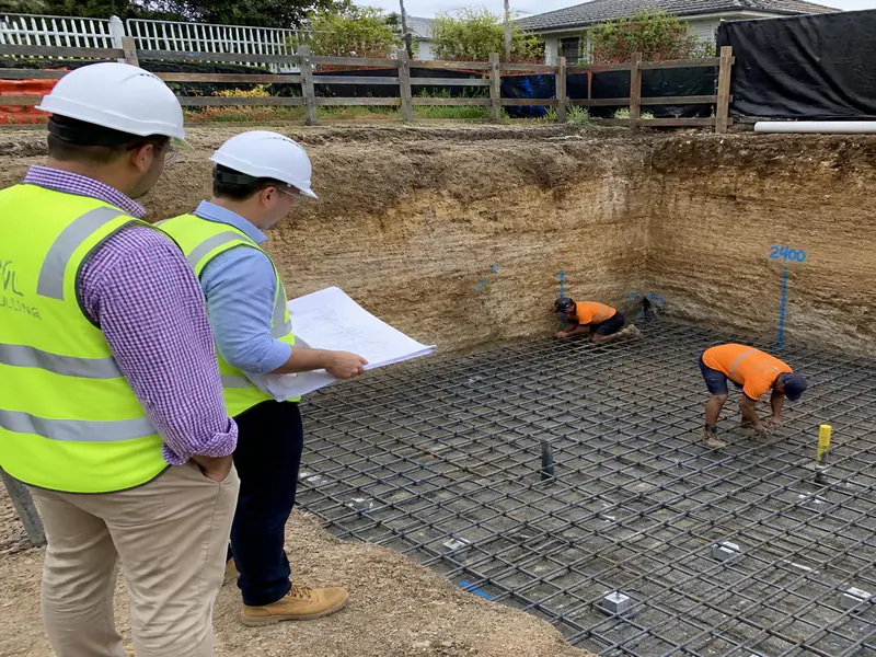 Civil engineers inspecting foundation excavation and reinforcement mesh on site