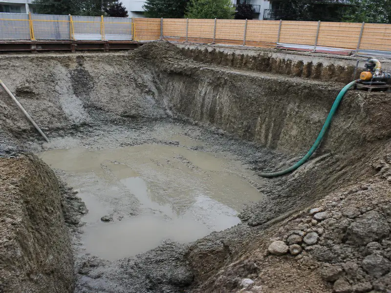 Excavated foundation pit with water table seepage at a construction site
